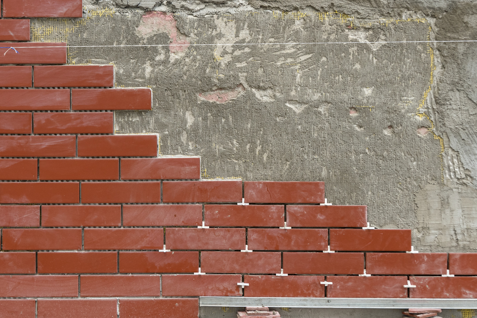 Wall or fence decoration. The technology of laying decorative tiles under a red brick on a vertical surface. Place for text